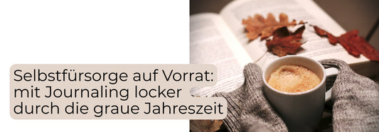 Tasse Tee in warmen Händen neben einem Herbstblatt – Journaling und Selbstfürsorge in der grauen Jahreszeit